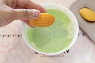 先做粉绿色玛德琳，将玛德琳的表面放入巧克力液内蘸一下。