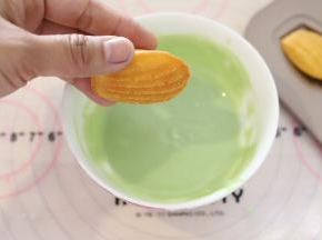 先做粉绿色玛德琳，将玛德琳的表面放入巧克力液内蘸一下。