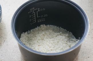 大米泡洗好之后入酷晨母婴电饭煲内胆里。将大米扒开一点。