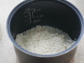 大米泡洗好之后入酷晨母婴电饭煲内胆里。将大米扒开一点。