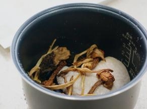 将泡洗好的菌菇及洗好的油鸡入饭煲里面。