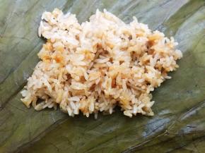 荷叶分成2份，取一份铺上一层糯米饭，铺平