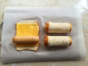 脆皮肠蒸好以后趁热取出，吐司片上铺一块芝士片，从下往上把脆皮肠全部卷起来