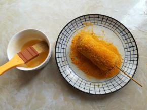 把黄色面包糠倒在一个大的盘子里，鸡蛋液里加一汤匙水混合均匀，用刷子在吐司片外面刷一层蛋液，让吐司片均匀的沾上面包糠香肠芝士卷的做法 步骤5
卷好的香肠芝士卷放到铺有