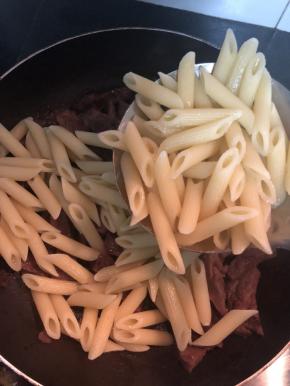 把通心粉放入装着牛肉的平底锅里，开小火慢慢翻炒均匀