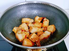 加入焯水的五花肉小火煸炒，炒制五花肉微黄。
