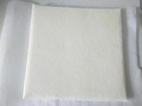 取出震一下烤盘，稍微晾一下，倒扣撕掉油布，再翻过来，把油布盖在蛋糕表面防止吹干。