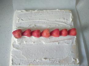 淡奶油加糖打发，先取出60克左右装入裱花袋，蛋糕两端斜切一部分，将奶油在蛋糕表面先抹薄薄一层，中间摆上草莓。