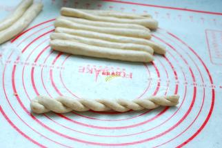 开始搓麻花吧，饧发好的面团取出其中的一个，搓成更长的长条，两手反方向让面团上劲，提起面团两端对折，很自然的扭成麻花状。