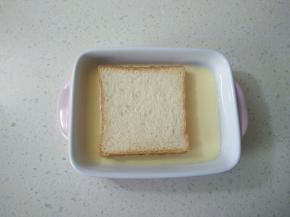 倒入烤盘，放一片土司片，按压土司片使充分吸收蛋糊。