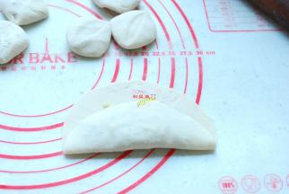 这个时候的面团也已经醒发好了，取出面团，揉匀，分成大小合适的小剂子，擀成圆片，取一个圆片，中间放入适量馅，先从一头向上折起来。