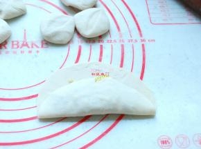 这个时候的面团也已经醒发好了，取出面团，揉匀，分成大小合适的小剂子，擀成圆片，取一个圆片，中间放入适量馅，先从一头向上折起来。