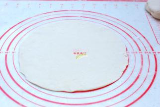 取其中一个面团，擀成薄一点的圆片。我这个大约是8寸，20mm。喜欢吃厚点儿面皮的可以少擀一圈，喜欢吃薄一点儿的面皮可以再擀薄点。