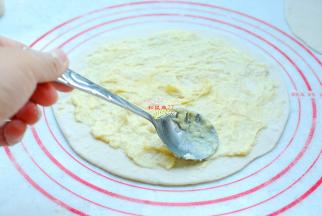 用小勺子把榴莲肉在小碗内加一点点盐压烂，然后均匀地涂在擀好的饼上，避开四周。加一点盐可以更好地突出榴莲的甜味。