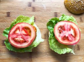 放入生菜，鸡腿肉，番茄，再放上一层生菜叶，盖上面包胚即可