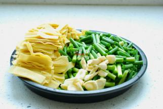 蒜薹择洗干净，切成长短合适的段，豆皮也切成和蒜薹差不多长短的段，再准备三瓣大蒜去皮清洗干净，切成蒜片。