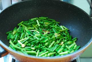 接着下入蒜薹，翻炒均匀，顺着锅边淋入1勺热水。现在的蒜薹大多都很嫩，不用炒太长时间，淋入热水后再翻炒两下。