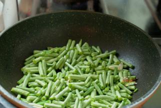 炒锅刷洗干净，烧热，放少量食用油，下入大蒜瓣煸炒出香味，把切好的长豆角放进去，翻炒均匀。