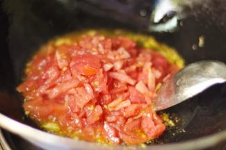 7、中火加入番茄不断翻炒，并不断的把番茄压碎，几乎看不到番茄块就好了