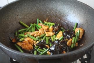 放入蒜苔和木耳，炒至蒜苔断生。