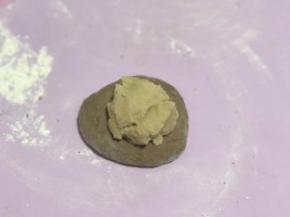 松弛完毕后，奶酥馅也分成6份，把面团按扁，取一份奶酥馅放入面团中。