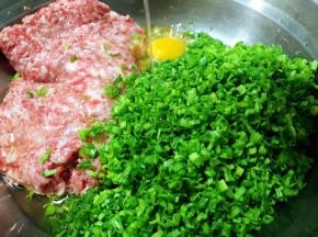 猪肉馅、蒜苗碎放入盆中，打入一个鸡蛋，倒入玉米油