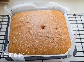 到时间后，用牙签插一下，拔出牙签看带出的蛋糕不发黏即可取出。牙签太短，不小心用手碰到蛋糕，哈哈，表面戳了个洞。提着油纸取出蛋糕放网架上，剥开油纸的四周散热放凉。