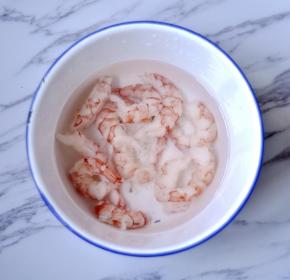 将虾放入冷水解冻，然后用厨房纸拭净水份，加盐、料酒、生粉，搅拌腌制