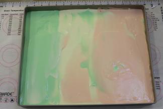 先将一个颜色的蛋糕糊倒入烤盘的三分之一处，再倒入另一个颜色的蛋糕糊，依次倒好三色的蛋糕糊。