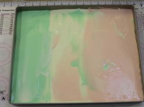 先将一个颜色的蛋糕糊倒入烤盘的三分之一处，再倒入另一个颜色的蛋糕糊，依次倒好三色的蛋糕糊。