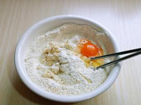将牛奶分次倒入面粉中，加入酵母粉，再磕入一个鸡蛋。