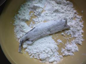 把沥干水份的多春鱼薄薄地挂上一层玉米淀粉，不需要太厚，因为这个鱼的皮非常薄，玉米淀粉的作用是防止鱼皮在煎的过程中破损。第二个作用是裹上淀粉的鱼皮煎完后会特别的酥脆。