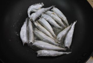锅烧热，然后加入花生油，加热至7成热。把挂好粉的多春鱼逐一放进锅里，中火煎至鱼的一面定型。煎鱼时不要乱翻动，要先把一面煎成金黄色再翻面。