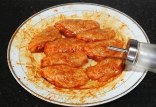 倒入所需分量的色拉油，

戴一次性手套把烤肉料与鸡翅中涂抹按摩均匀，