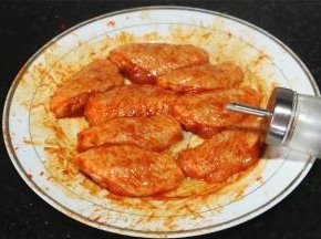 倒入所需分量的色拉油，

戴一次性手套把烤肉料与鸡翅中涂抹按摩均匀，