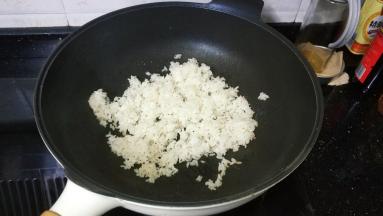 章鱼丸切成小粒备用；锅里热油倒入一碗剩米饭翻炒均匀