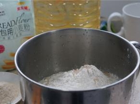 现在我们先来揉面，将液态食材全部先加入，然后再加入称量好的面包粉及酵母。