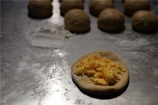 然后将面团擀压一下，将调好的椰蓉馅料包在里面。