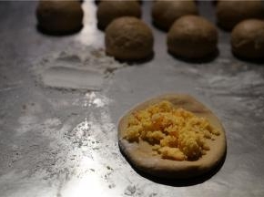 然后将面团擀压一下，将调好的椰蓉馅料包在里面。