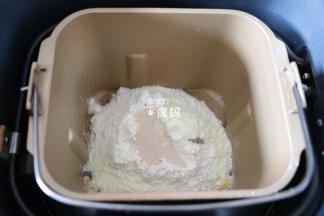 将水、蛋液倒入面包机的面包桶中，盐、糖对角放，再倒入面包粉和奶粉，粉中间挖个洞放入干酵母粉，启动面包机和面程序开始揉面；