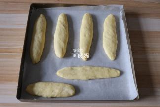 将每个面团都搓成细长条放入烤盘，用手稍微压扁后进行二次发酵；