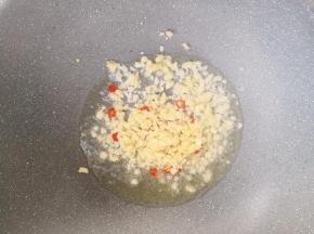 锅中倒入少许油，放入蒜末和小米辣，小火炒出香味。