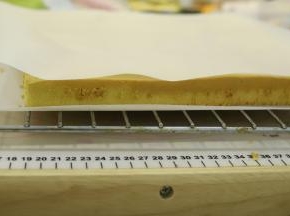 出炉的蛋糕卷轻震一下，放2分钟后倒扣备用。