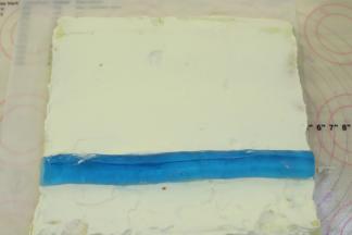 淡奶油抹好整个蛋糕卷的反面，心形蓝色白凉粉脱模，放在蛋糕卷的三分之一处。