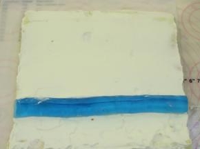 淡奶油抹好整个蛋糕卷的反面，心形蓝色白凉粉脱模，放在蛋糕卷的三分之一处。