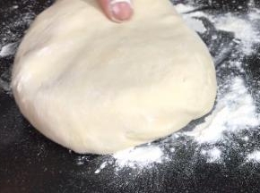 案台上撒上干粉，取出面团按成圆饼