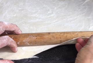 再撒一层干粉，用擀面杖把面皮卷成卷