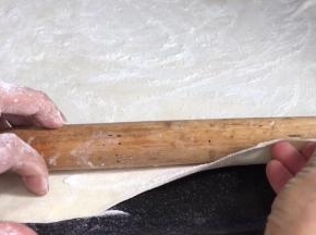 再撒一层干粉，用擀面杖把面皮卷成卷