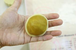 饼皮压成中间稍厚边缘薄的圆片，包住月饼馅。