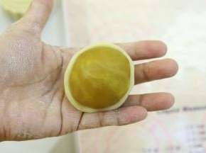 饼皮压成中间稍厚边缘薄的圆片，包住月饼馅。